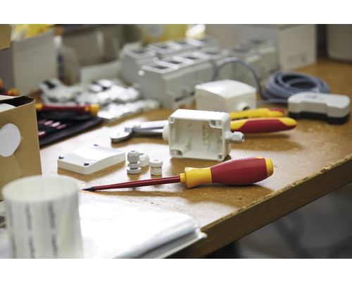 Foto van een selectie elektriciensgereedschap en installatiematerialen op een werkblad.
