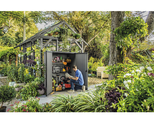 Scene met een tuinhuisje gevuld met tuingereedschap en -uitrusting, omringd door weelderig groen