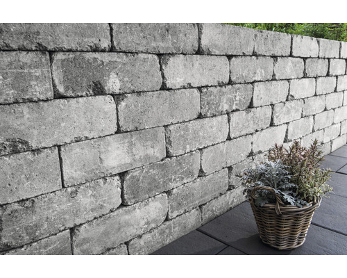 Grijze tuinafscheiding van betonstenen met plantenmand