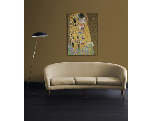 Schilderij De Kus van Gustav Klimt aan de muur boven een bank