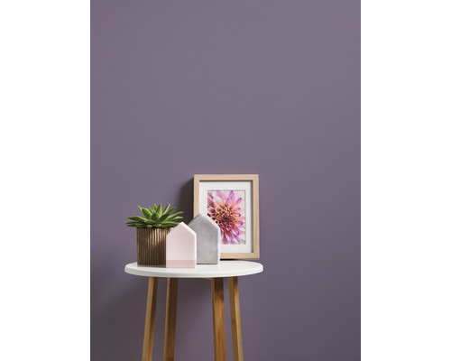 Decoratieve scène met potplant, huisdecoraties en een ingelijste afbeelding op een klein tafeltje voor een muur