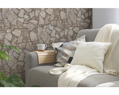 Woonkamer met stenen muur, bank, kussens, deken en beker