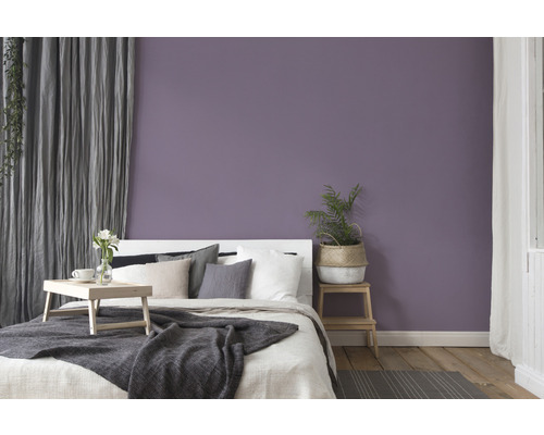 Slaapkamer met bed, houten vloer en paarse muur