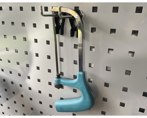 Beugelzaag met kunststof handgreep aan een geperforeerde wand