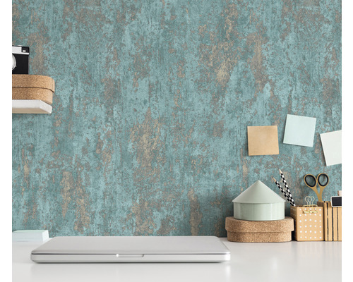 Scene met een gestructureerd behang, een laptop en kantoorartikelen op een wit bureau.