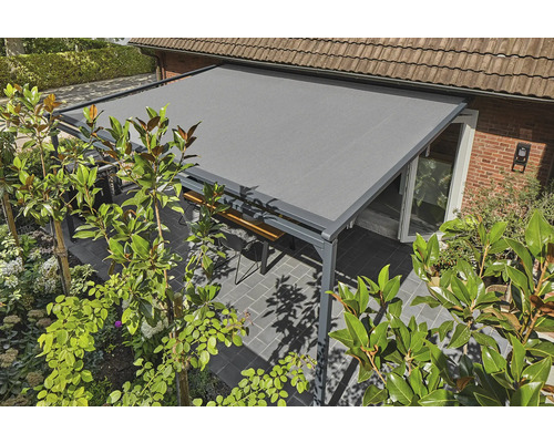 Grijze terrasoverkapping met zithoek in de tuin.