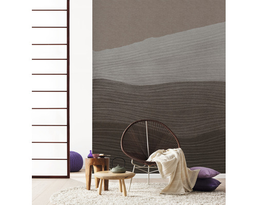 Woonkamer met behang met patroon, fauteuil, vloerkleed en bijzettafels