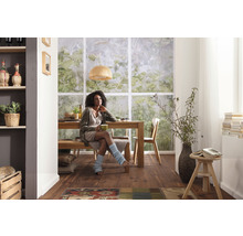 Lichte eetkamer met houten tafel, bank, stoelen en een vrouw.