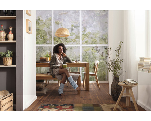 Lichte eetkamer met houten tafel, bank, stoelen en een vrouw.