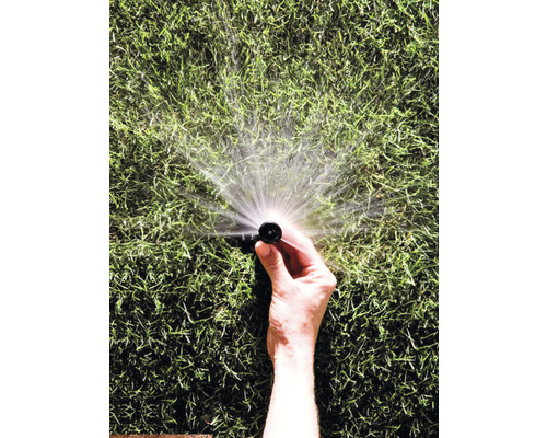 Een hand houdt een gazonsproeier vast die water sproeit.