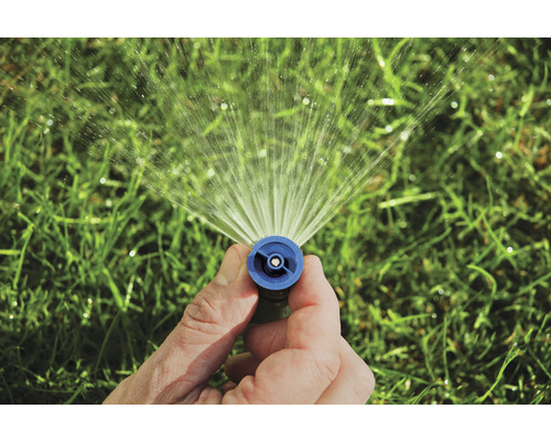 Een hand houdt een gazonsproeier vast die water sproeit