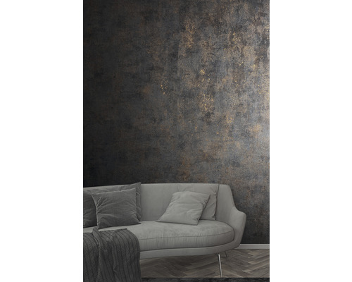 Woonkamer met grijze bank en donker structuurbehang met gouden accenten.
