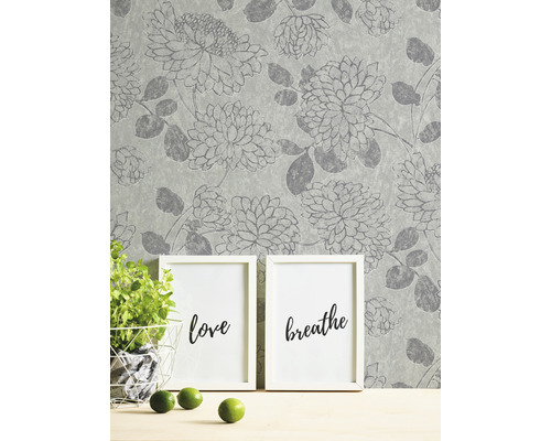 Behang met bloemmotief, twee fotolijsten, potplant en limoenen op een tafel