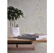 Scene met een beige behang met bloemmotief, een houten tafel met een plant en boeken