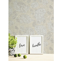 Behang met bloemmotief, twee fotolijsten met de woorden Liefde en Adem, potplant en limoenen op een tafel