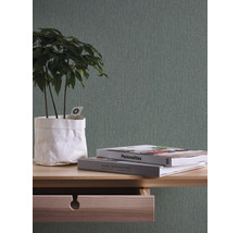 Close-up van een tafel met open lade, boeken en een plant erop, tegen een gestructureerd behang.
