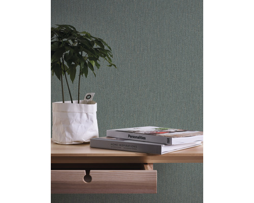 Close-up van een tafel met open lade, boeken en een plant erop, tegen een gestructureerd behang.