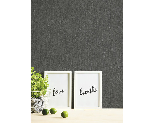 Close-up van een grijs textielbehang met de woorden love en breathe in fotolijsten, potplant en limoenen