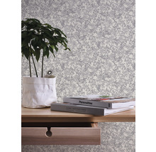 Decoratief behang met bladerpatroon, gecombineerd met plant en boeken op een houten plank.