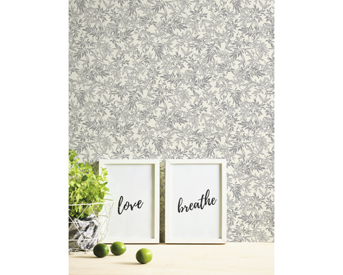 Decoratief behang met plantenmotief op de achtergrond, gecombineerd met twee afbeeldingen en een plant.