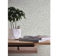 Close-up van een kamer met een bureau, een potplant en behang met bladeren