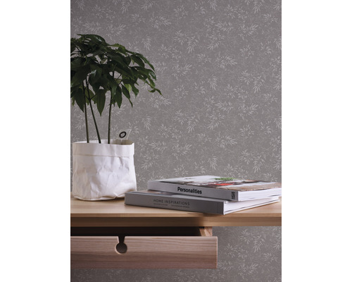 Afbeelding van een kamer met een behang met motief, een tafel met een plant en boeken