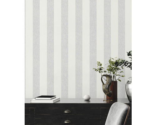 Interieurscène met gestreepte behang, dressoir, boeken en decoraties voor een moderne kamerinrichting.