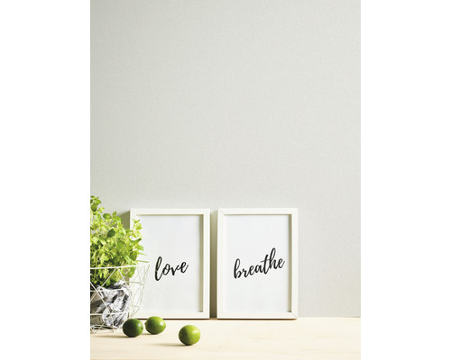Decoratieve fotolijsten met de opschriften liefde en ademen, samen met een plant en limoenen op een tafel.