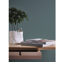 Decoratief stilleven met plant in papieren zak, boeken en ladekast