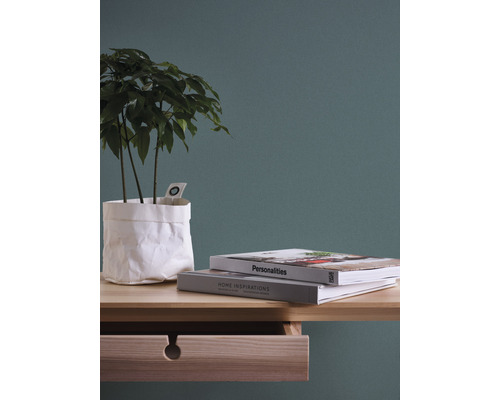 Decoratief stilleven met plant in papieren zak, boeken en ladekast