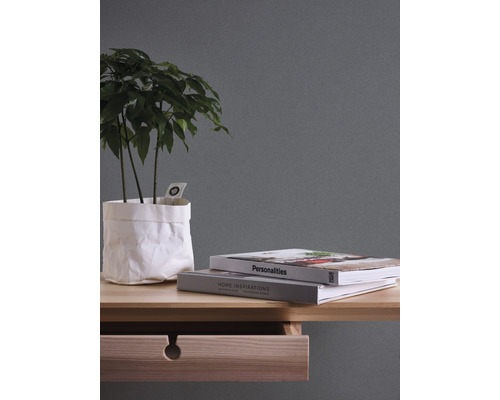 Decoratieve kamerplant in papieren zak op een bureau met boeken