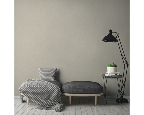 Lichte ruimte met textielbehang, zitmeubel, vloerlamp en bijzettafel.