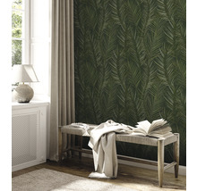 Een kamer met een wandbehang met palmenbladmotief, een raam, een radiator en een bank.