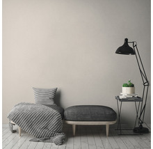 Inrichtingsvoorbeeld met zitbank, lamp en decoratief textiel in een lichte ruimte.