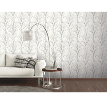 Woonkamer met witte bank en een muur met behang met takkenpatroon