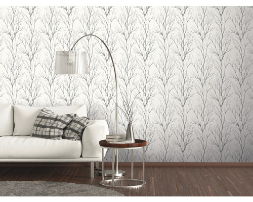 Woonkamer met witte bank en een muur met behang met takkenpatroon