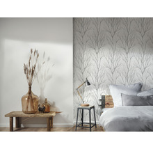 Een slaapkamer met een bed, een nachtkastje en een muur met boombehang.