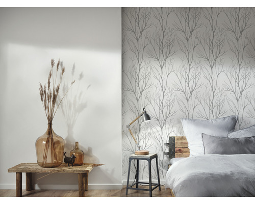 Een slaapkamer met een bed, een nachtkastje en een muur met boombehang.