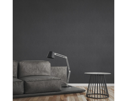 Woonkamer met bank, staande lamp en bijzettafel voor een donkere muur