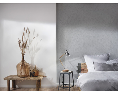 Lichte slaapkamer met een bed, een lamp en decoratieve elementen op een houten tafel