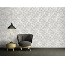 Woonkamer met patroonbehang, fauteuil, bijzettafel en hanglamp