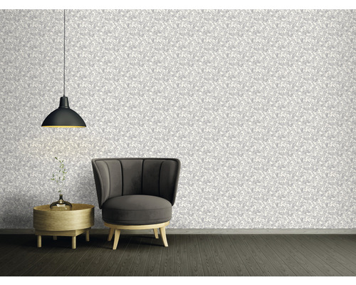 Woonkamer met patroonbehang, fauteuil, bijzettafel en hanglamp