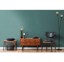 Woonkamerinterieur met houten commode, stoel, staande lamp en decoratie op parketvloer voor een gekleurde wand