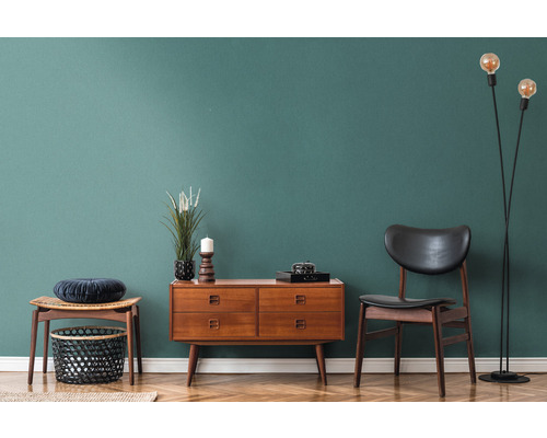 Woonkamerinterieur met houten commode, stoel, staande lamp en decoratie op parketvloer voor een gekleurde wand