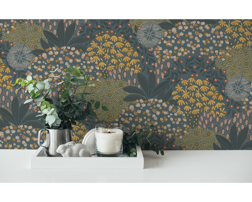 Decoratief behang met bloemmotief, gecombineerd met kaars, zilveren kruik en eucalyptus op een witte tafel.
