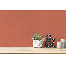 Close-up van een muur met textielbehang, kamerplant, decoratieve letters en keramische bekers op een tafel