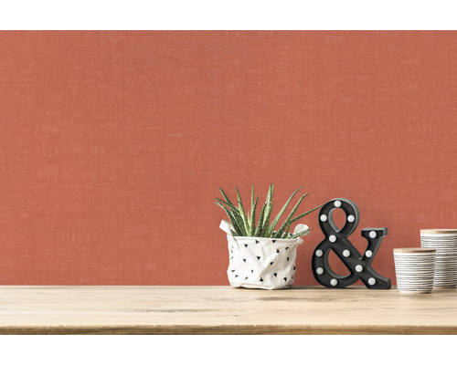 Close-up van een muur met textielbehang, kamerplant, decoratieve letters en keramische bekers op een tafel