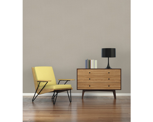 Woonkamer met fauteuil, houten ladekast, lamp en boeken