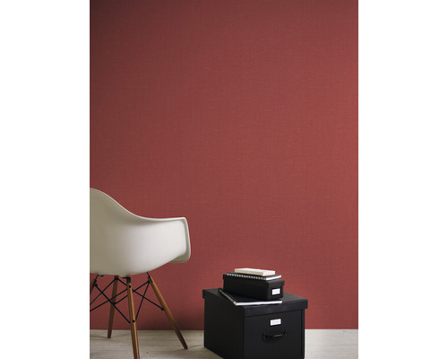 Woonkamer met rood structuurbehang, een witte stoel en zwarte opbergdozen