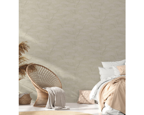 Slaapkamer met rotan stoel, bed en behang met print voor een lichte, vriendelijke sfeer.